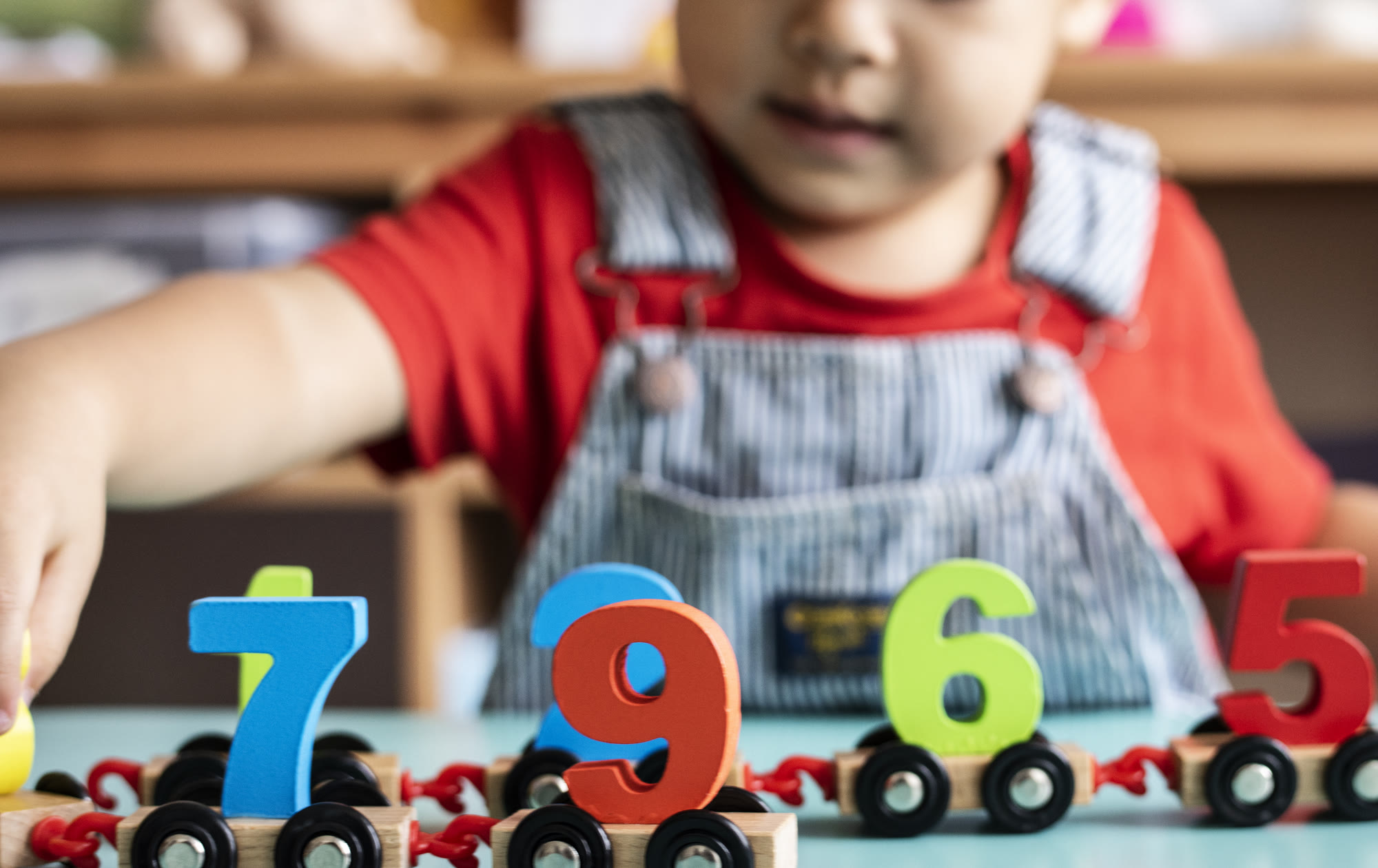 A child playing with a wooden number train at nursery