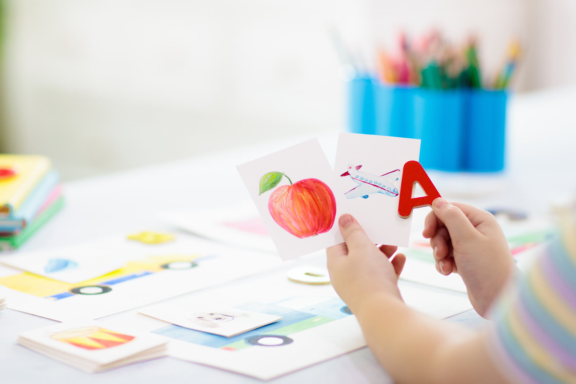 A child holding up alphabet flash cards and a letter A